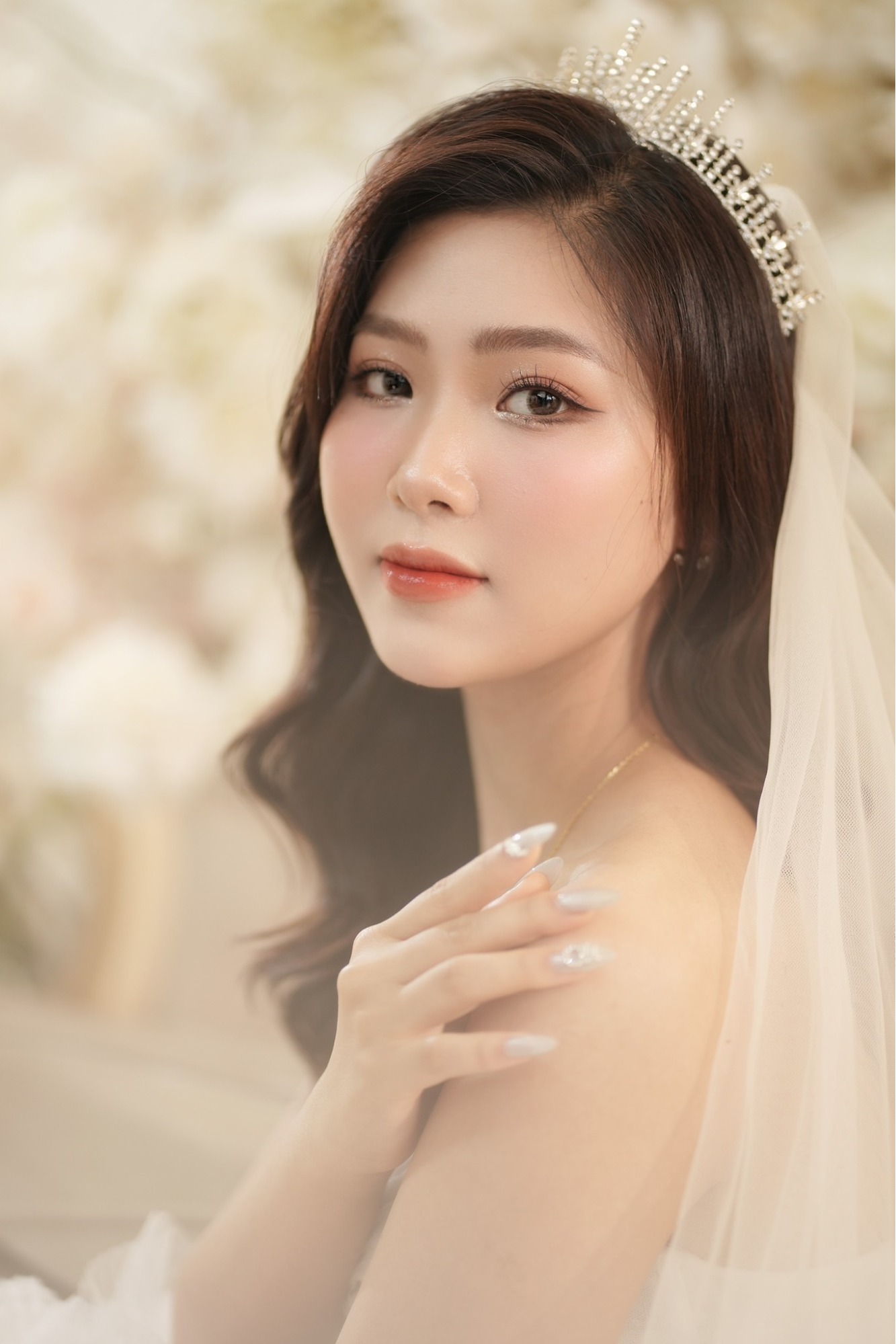 Mẫu tóc dài xoăn nhẹ rẽ lệch ngôi đội vương miện đẹp cho dâu